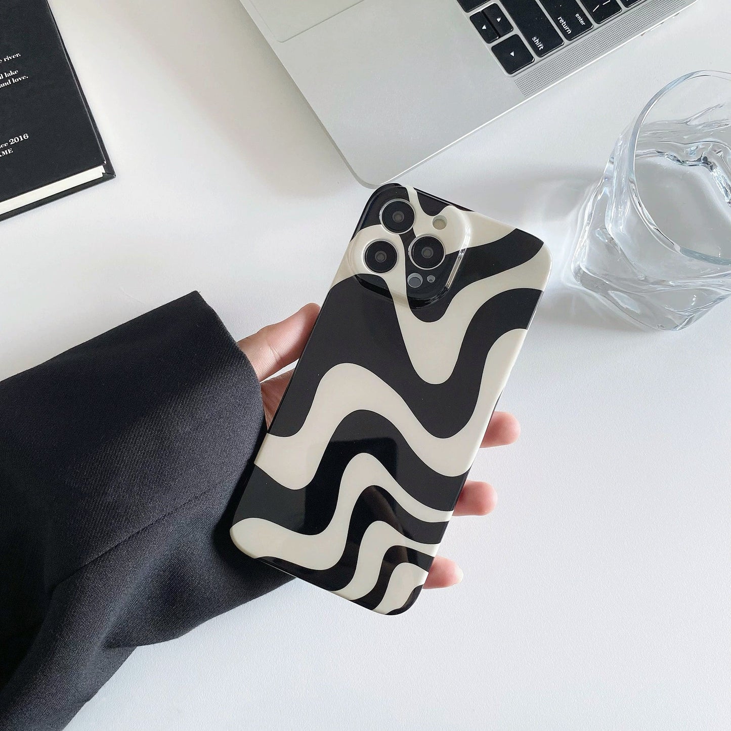 Model holding Black Wave Phone Case. Sleek wave-texture finish in durable acrylic, perfect for modern edgy fashion.