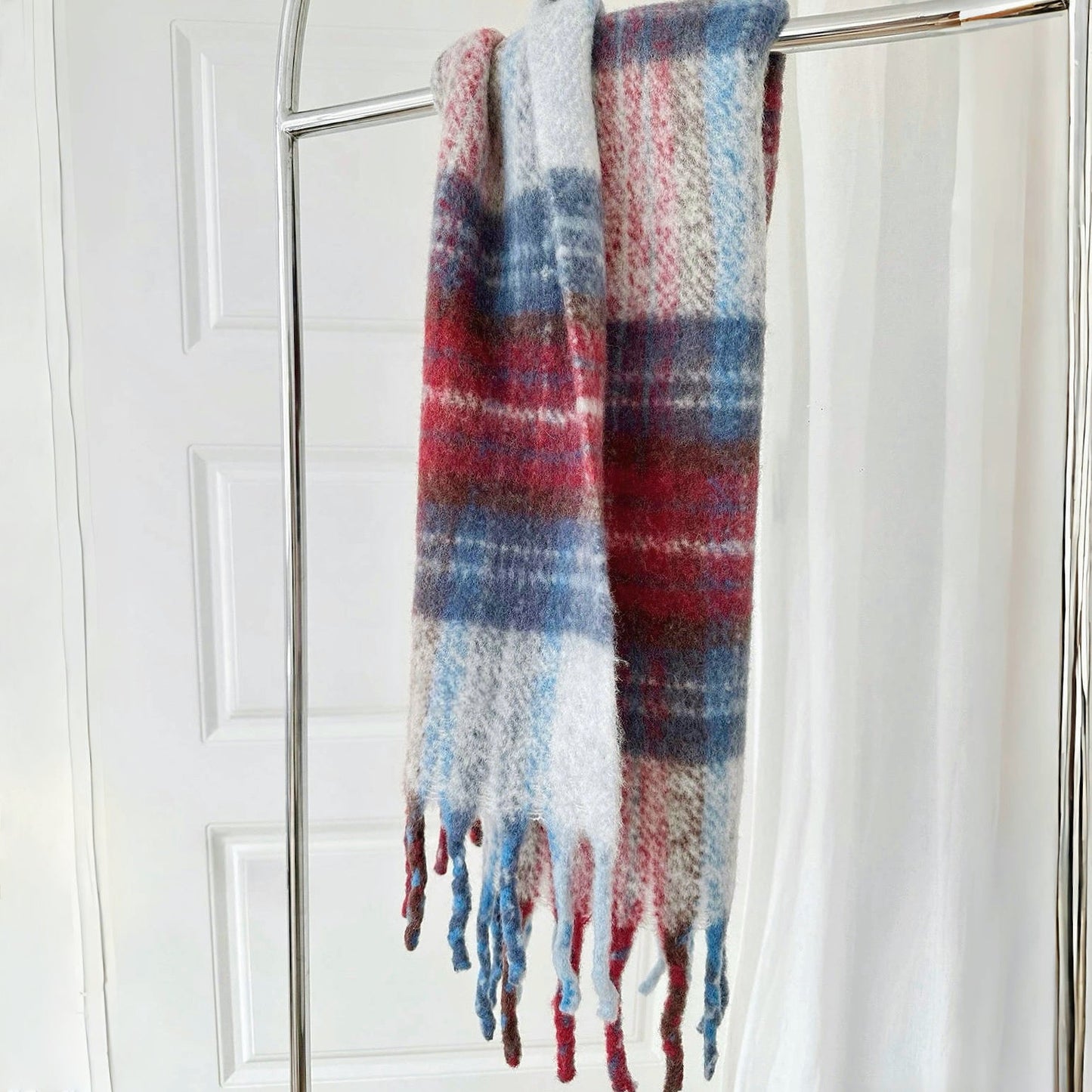Flat lay of Crimson Meadow Plaid Scarf in blue and red, great for office layering and commuting.