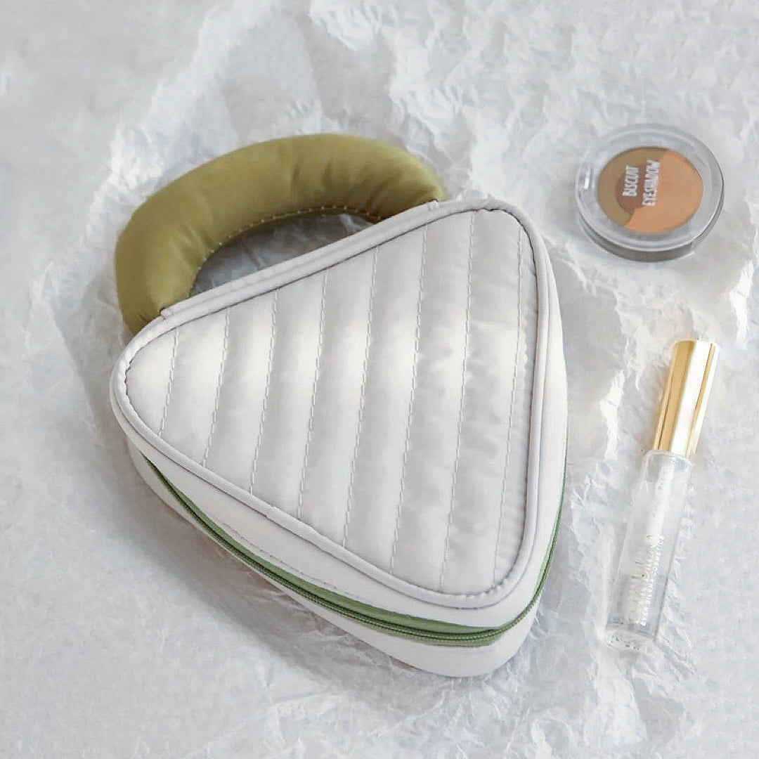 White Puffy Candy triangle mini bag with olive handle; quilted zip case styled with makeup for travel-ready packing.