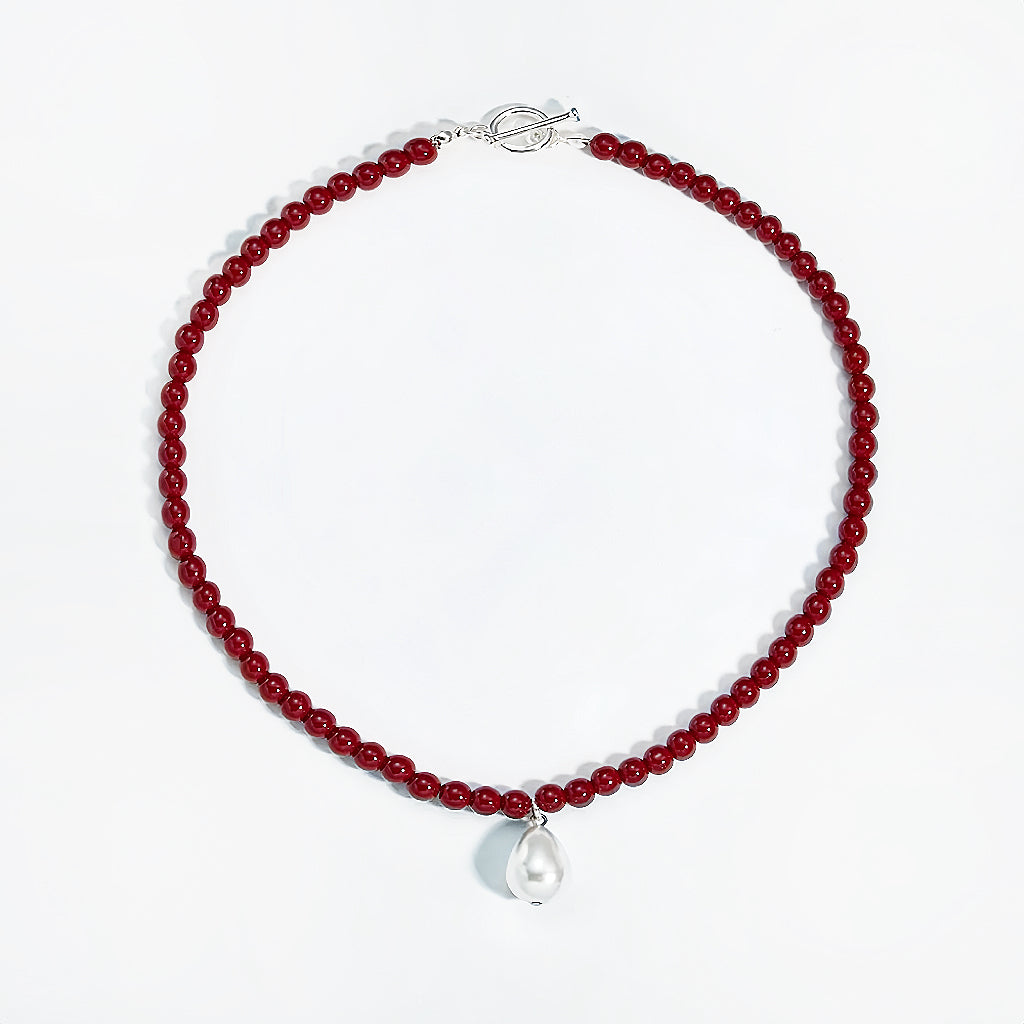 Flat lay of red rose dew necklace showing artificial pearl drop and toggle clasp