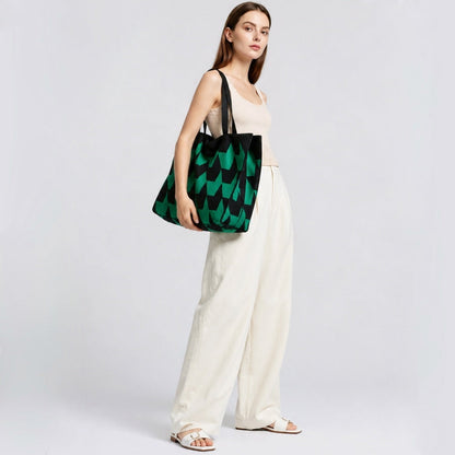 Model carrying oversized arrow print tote bag with green and black geometric pattern, trendy urban streetwear styling.