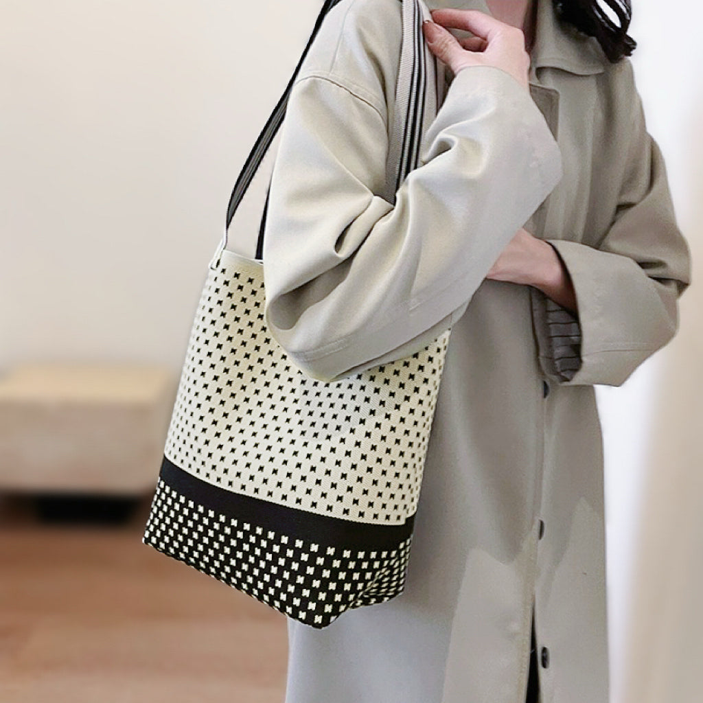 Model styling the cream dotted artistic pattern bucket bag with a neutral outfit.
