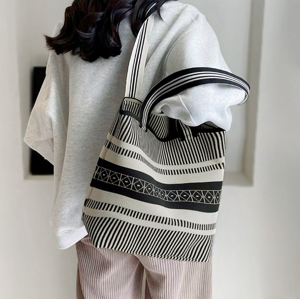 Model carrying the white and black artistic pattern bucket bag over the shoulder.