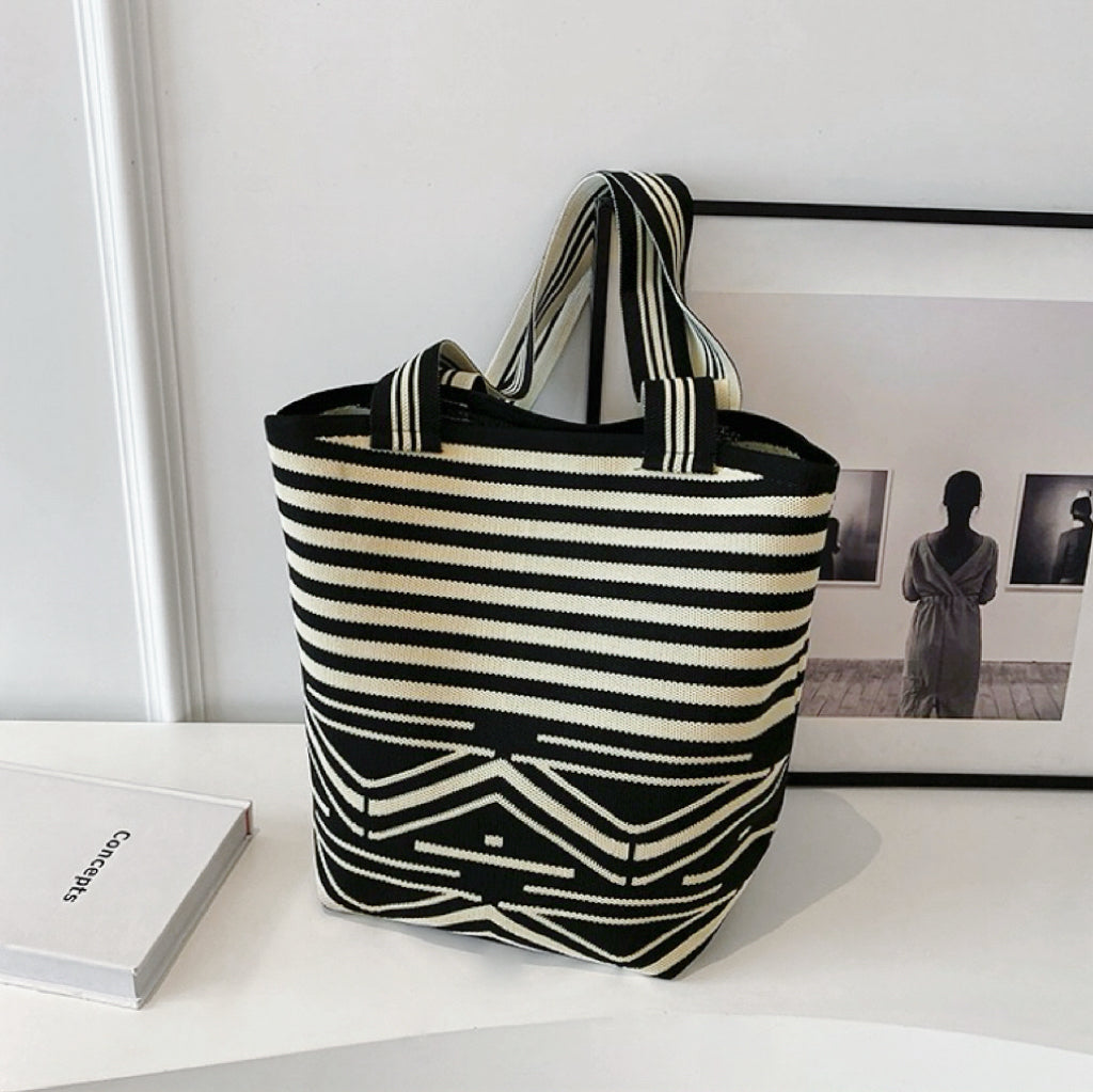 Artistic bucket bag featuring a complex mix of horizontal stripes and geometric patterns.