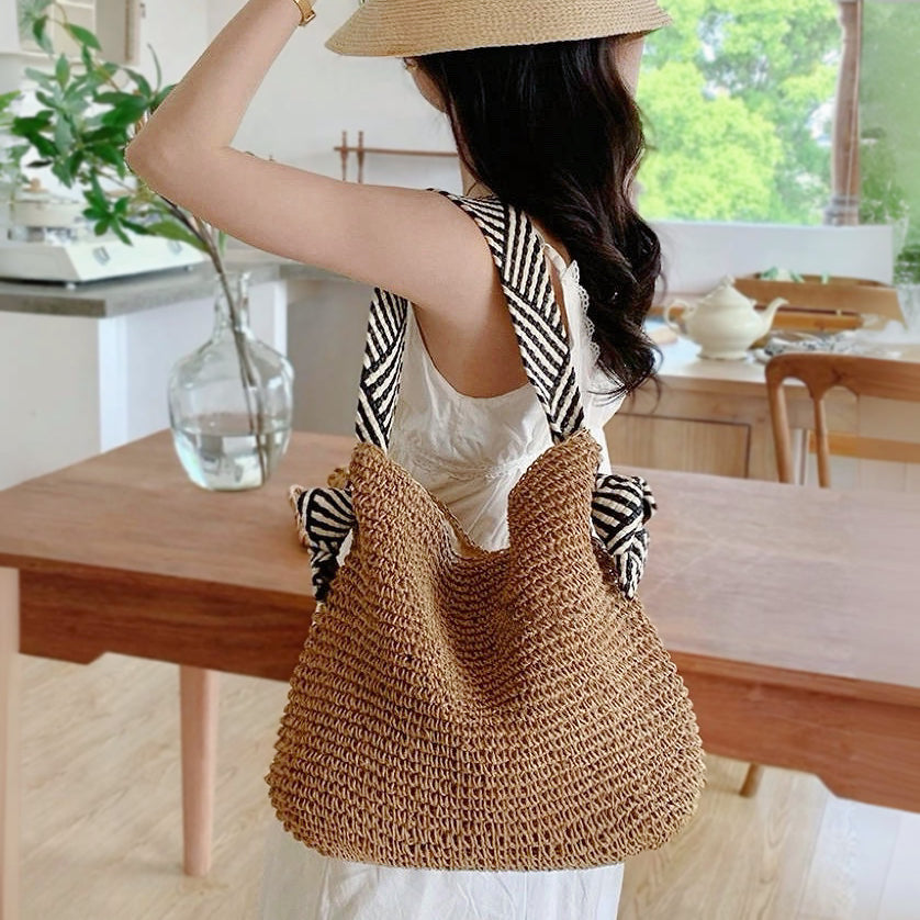 Model carrying the striped straw bag for a bohemian summer look.