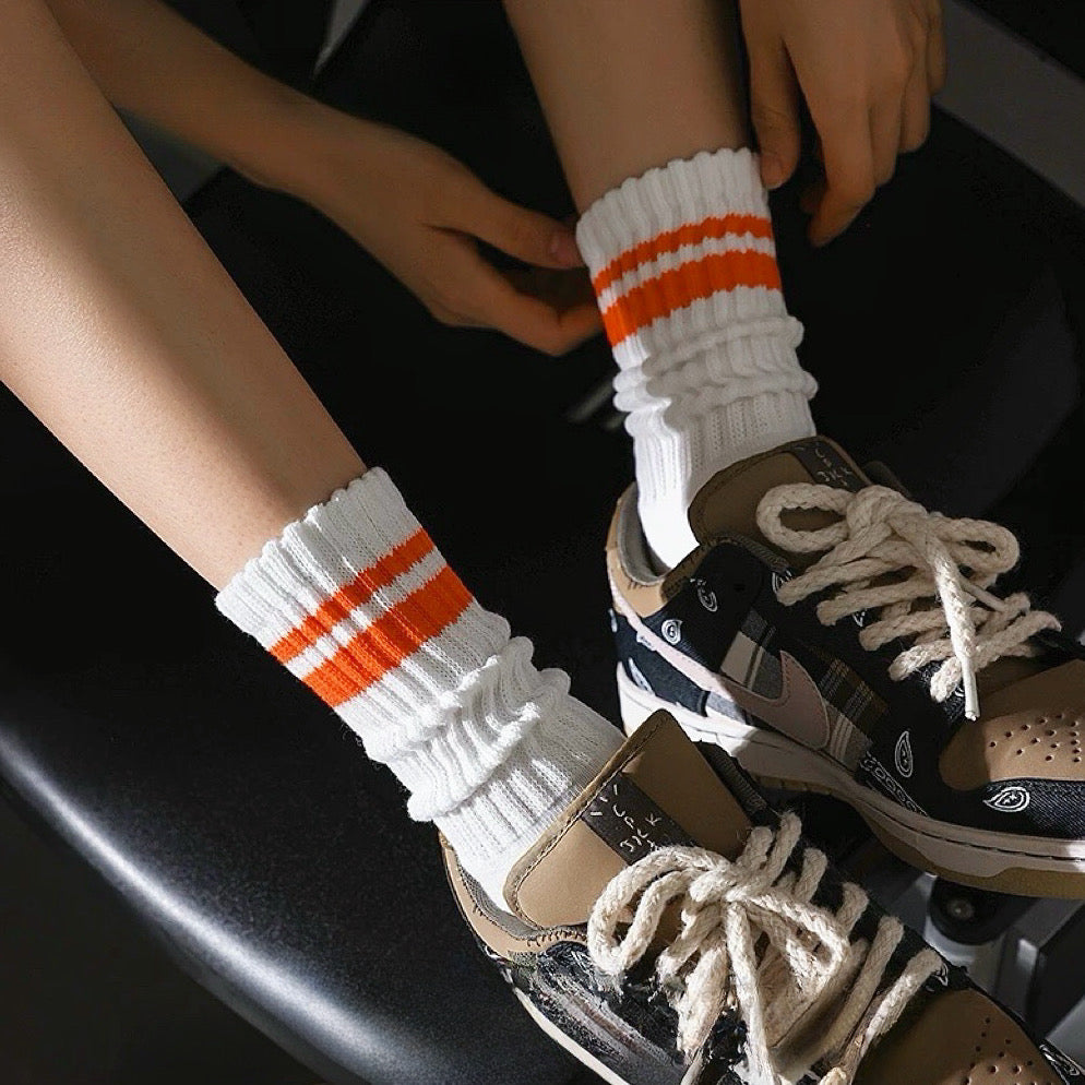 Model wearing a pair of orange striped cotton socks, ideal for everyday outfits and sneakers.