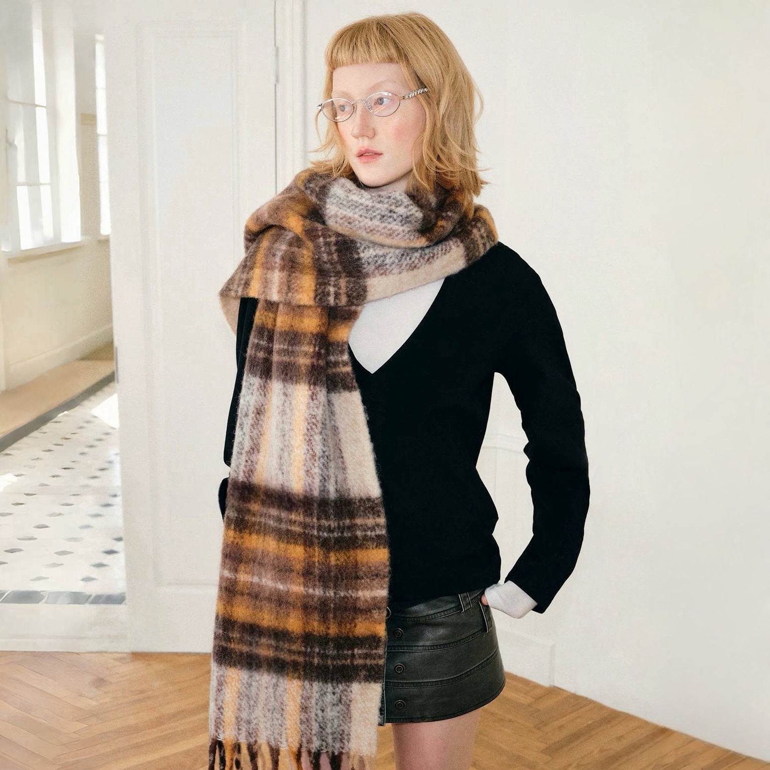 Model wearing Autumn Ember Plaid Scarf, a wool blend, fringed scarf with brown, orange, and cream checks.