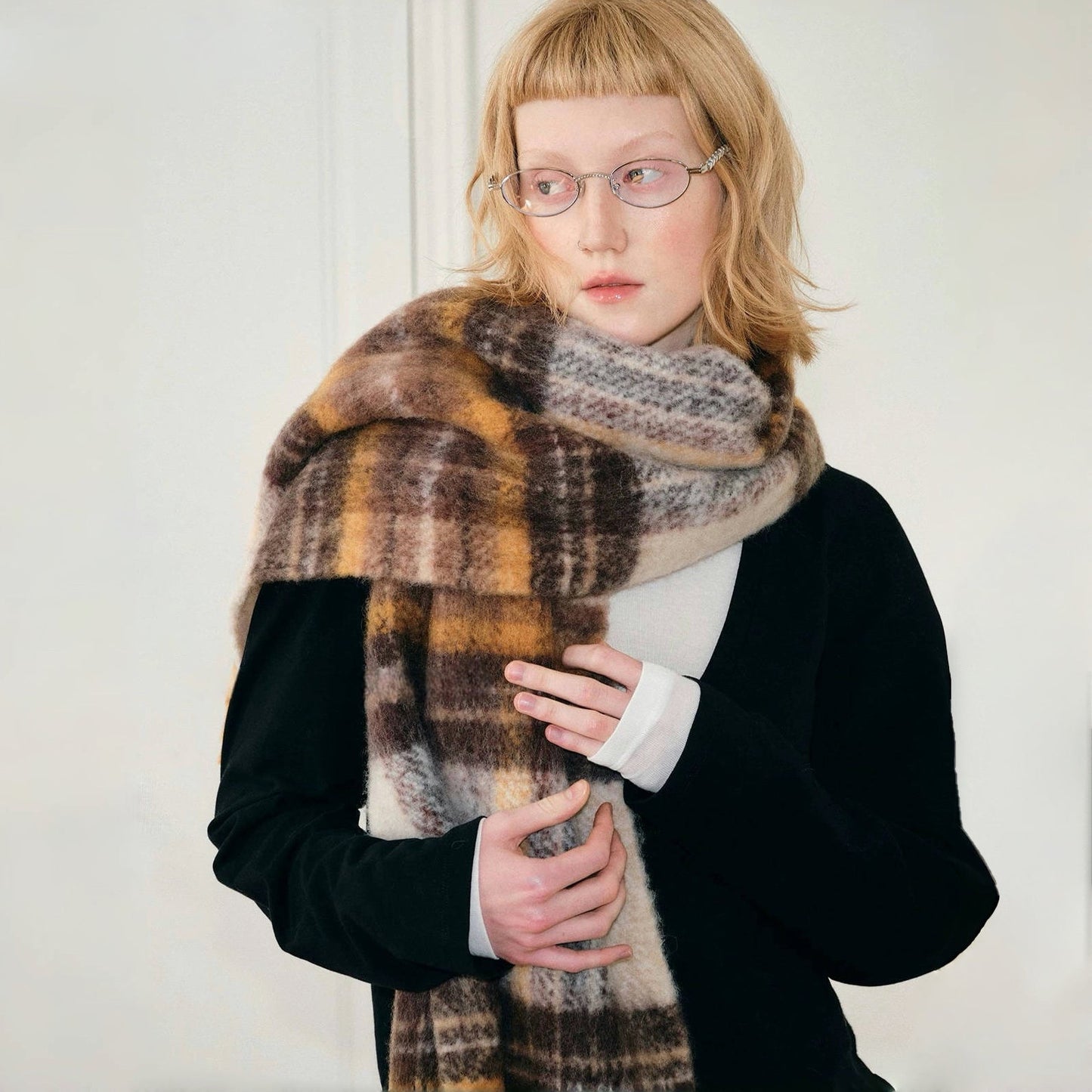 Model wearing cozy Autumn Ember Plaid Scarf, a wool blend in warm brown, gold, and cream tones in yellow.