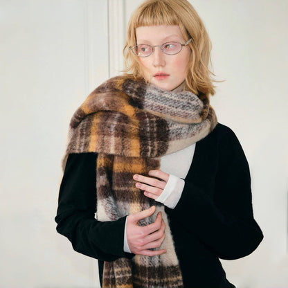 Model wearing cozy Autumn Ember Plaid Scarf, a wool blend in warm brown, gold, and cream tones in yellow.