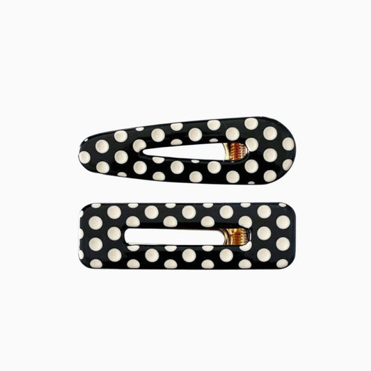 Two black acrylic hair clips with white polka dots, one is arrow shape and one is rectangular.