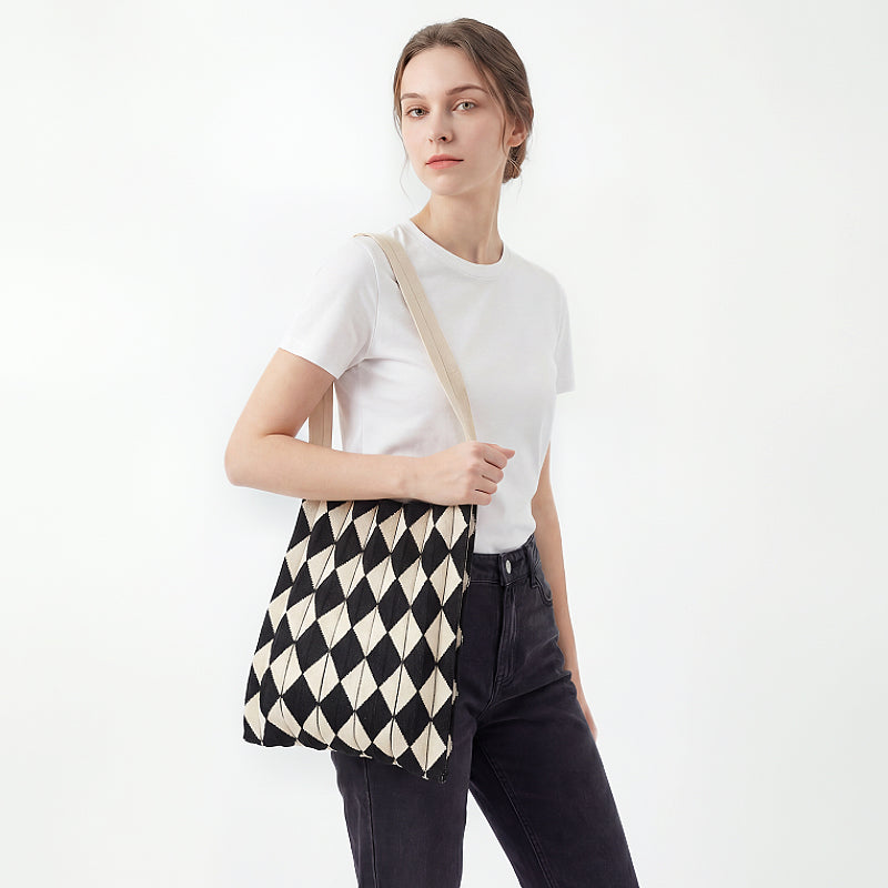 Model styling a black and beige argyle pleated knit bag for a minimalist  style