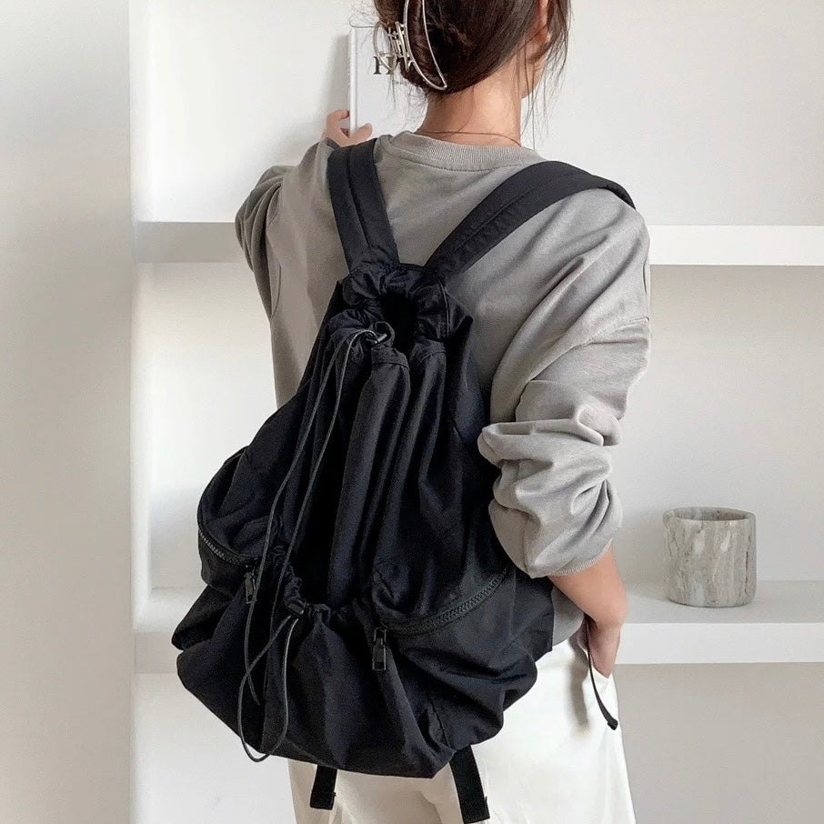 Model wearing black foldable backpack made of waterproof polyester, perfect for urban utility style.