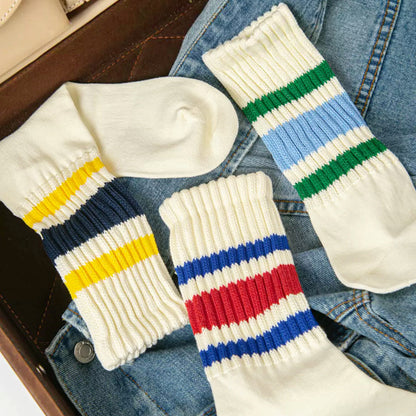 Angled view of Three pairs of Blockcore Slouch Socks in white cotton-polyester, each with colorful striped cuffs.