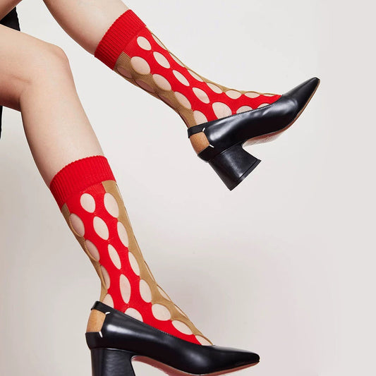 Model wearing a pair of red and beige Bold Hollow Socks with large polka dot cutouts.