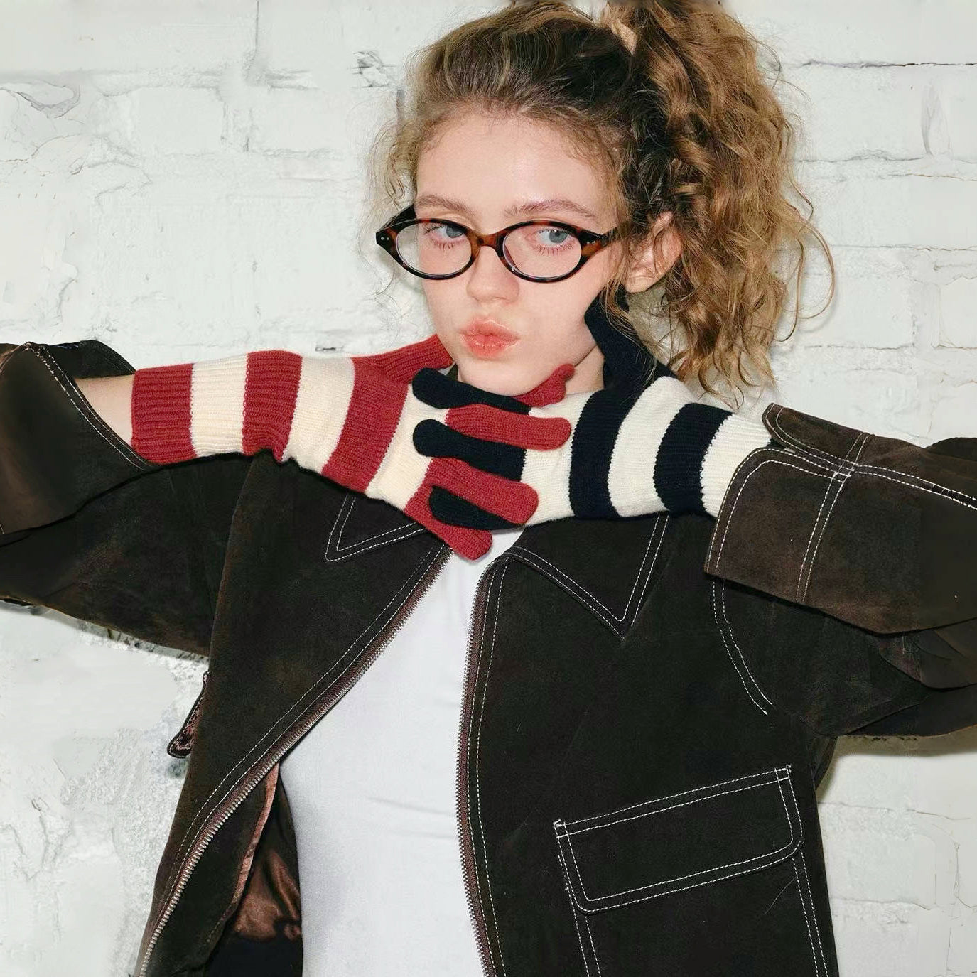 Model wearing bold stripe knit gloves with red, cream, and navy bands; cozy for cold-day street outfits.