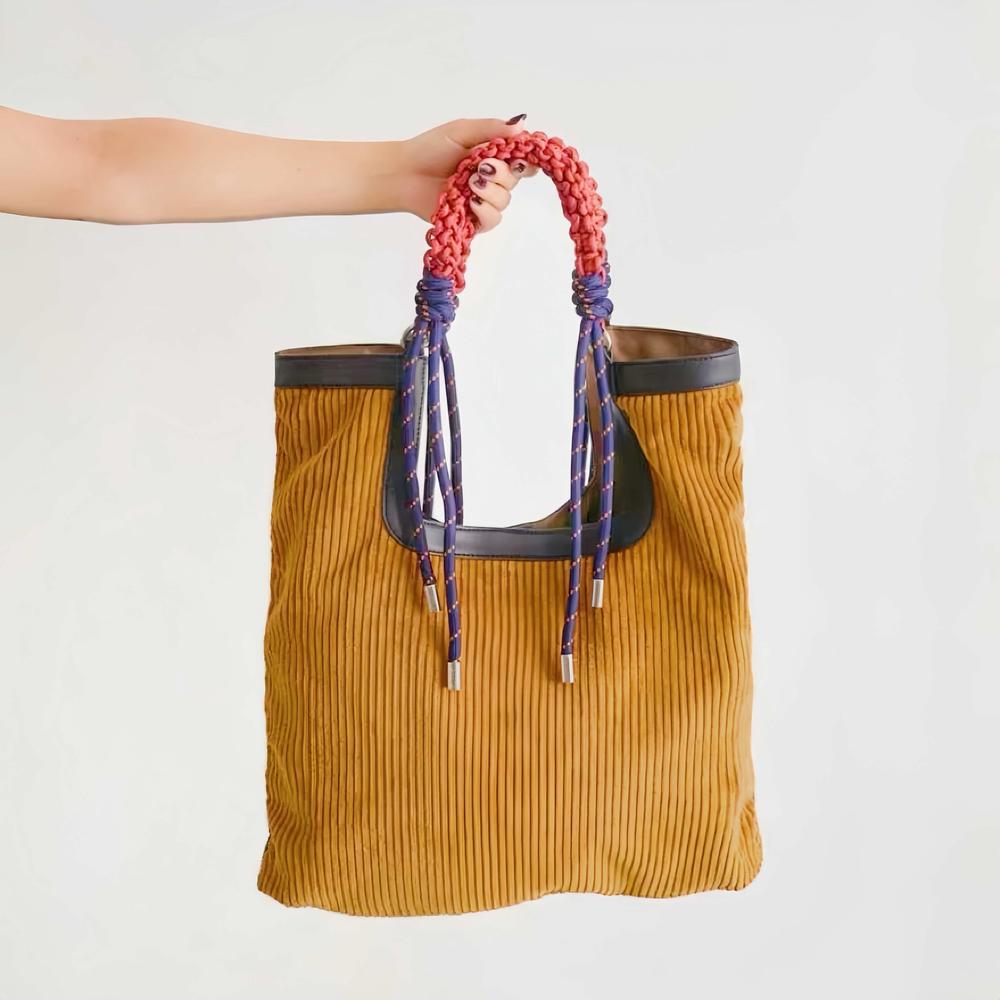 A hand holding the Designer Gentle Beam Tote Bag by its unique  braided rope handle against a white background.