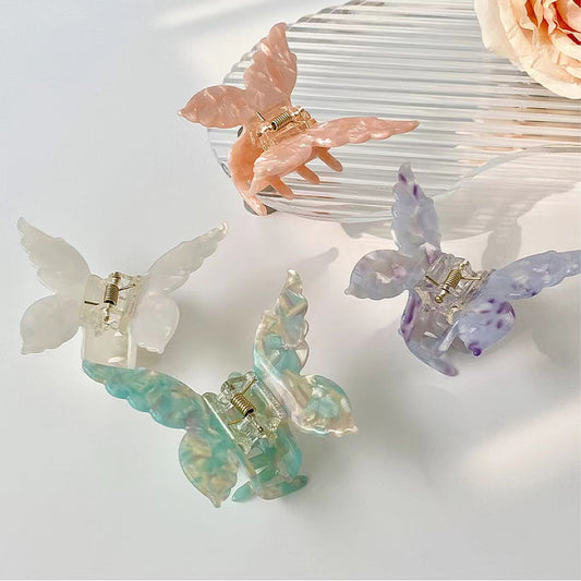 Four acrylic butterfly hair claws in white, pink, purple, and green with alloy springs.