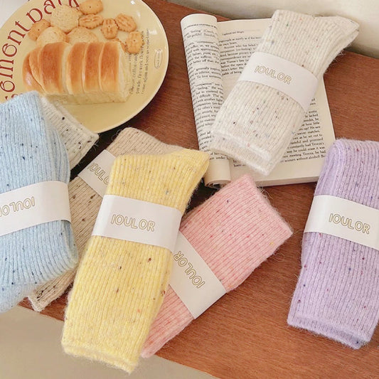 Group of rolled-up candy speckled wool socks in various pastel colors.