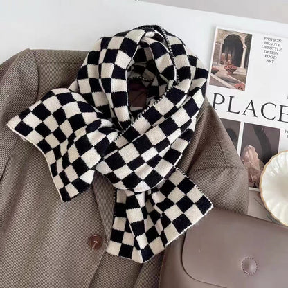 Angled view of Black and white checkerboard wool blend scarf draped over a brown blazer, easy for travel.