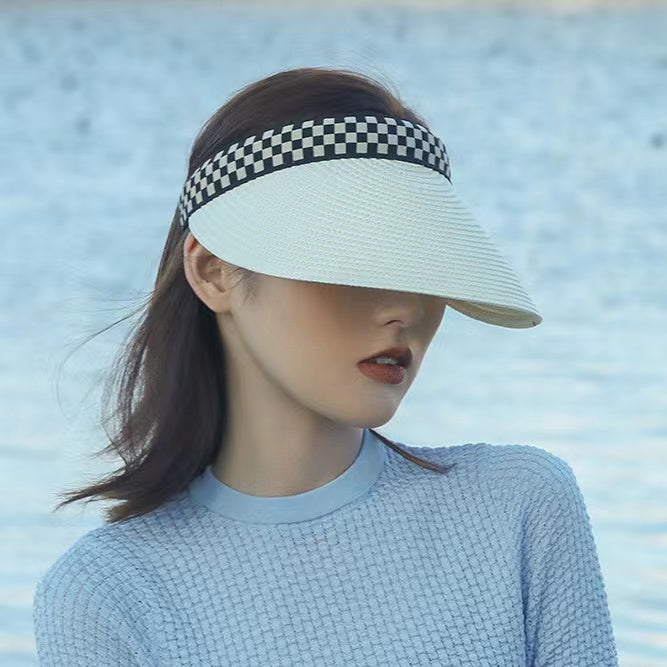White straw visor hat featuring a stylish black and white checkered band on a model.