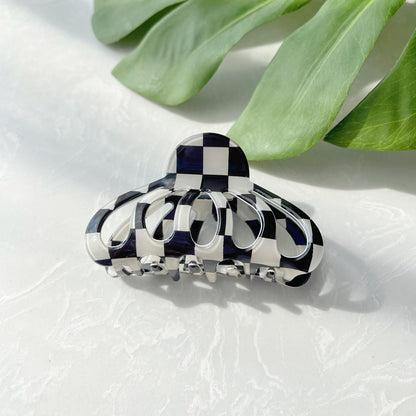 Flat lay of checkered hair claw hair claw clip in lantern shape, great for everyday styling and gifting.