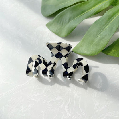 Close-up of checkered hair claw in mcross shape, easy for workdays and special occasions.