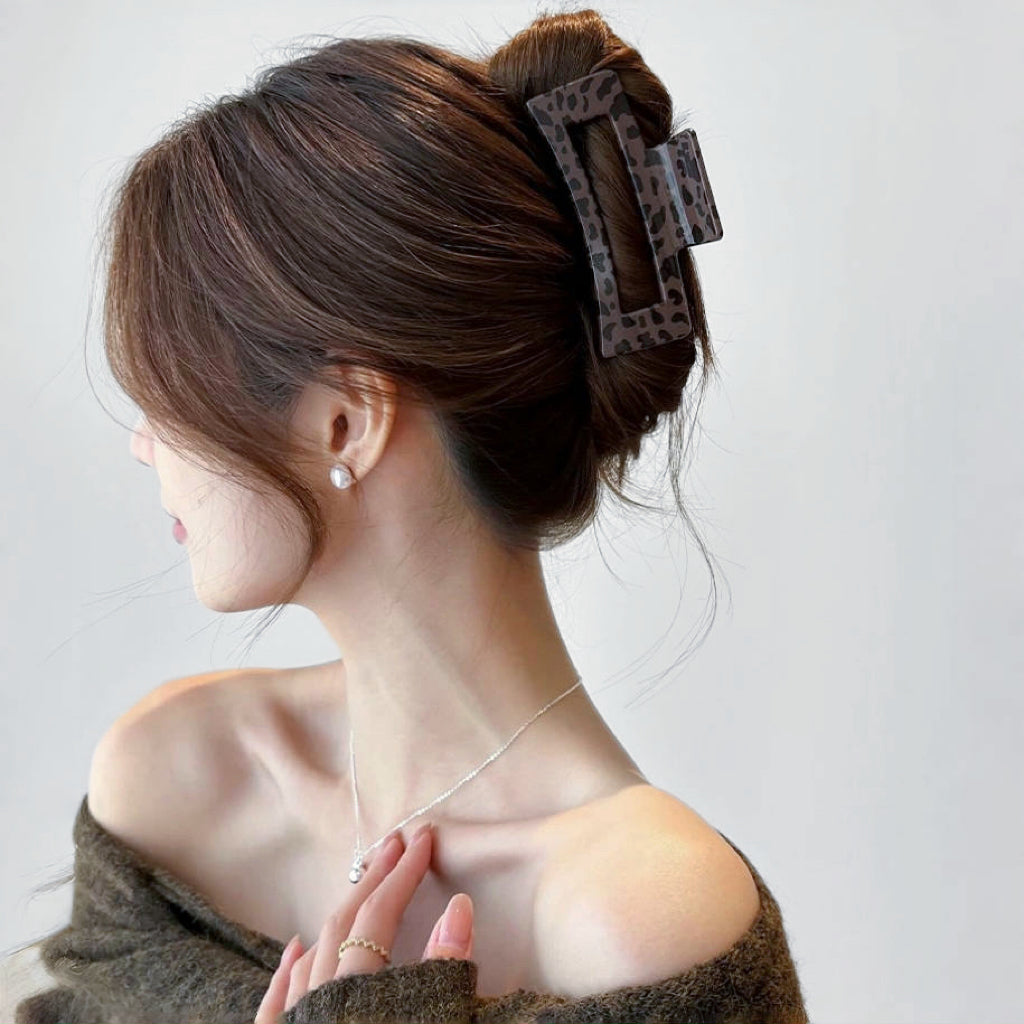Model wearing a dark Chocolate Leopard Print Hair Claw in square shape.