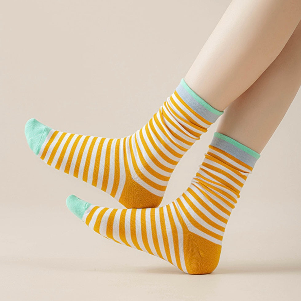 Model wearing a pair of Chromatic Stripe Socks in yellow, easy to pack for travel and errands.