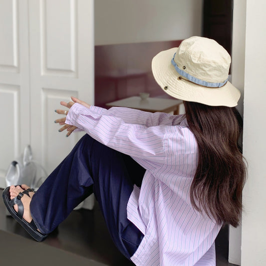 Beige nylon Colorband Flip Bucket Hat with blue band, worn by a person sitting.