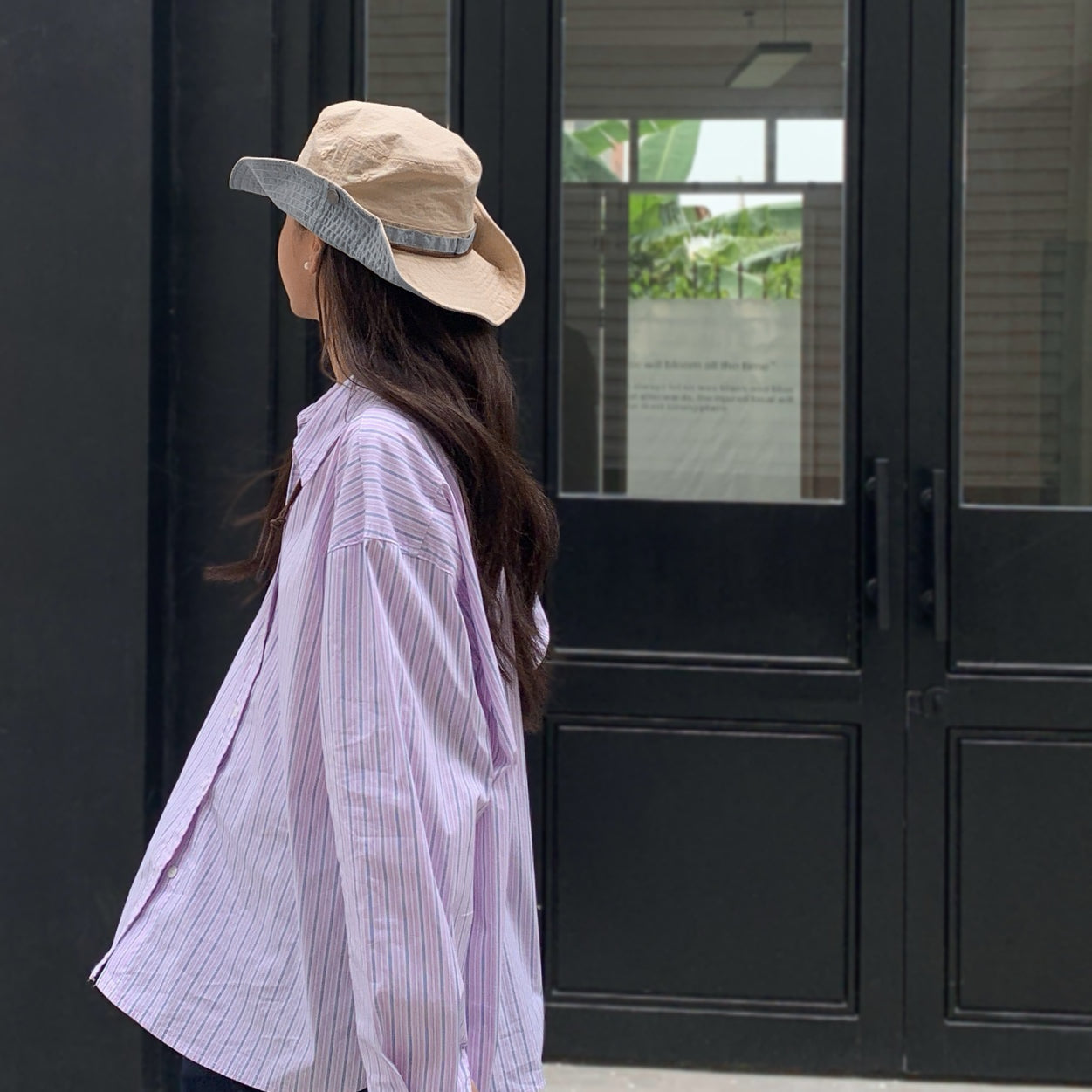 Back view of model wearing the khaki bucket hat with the snap-up brim for a cowboy hat style.