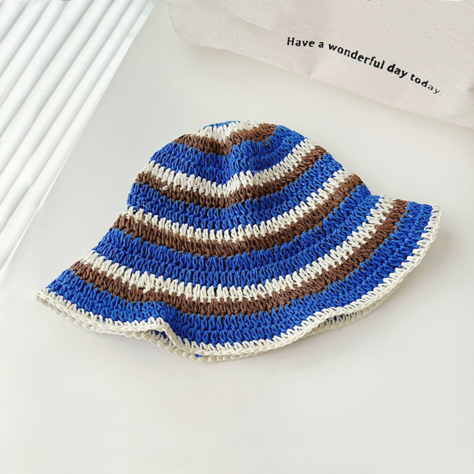 Front view of blue striped foldable straw hat. Refreshing nautical theme for comfortable travel and sunhat.