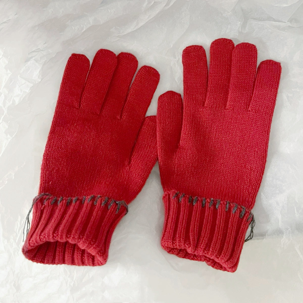 Red colored-thread hemming gloves with contrast stitched edges; cozy knit gloves for winter days.
