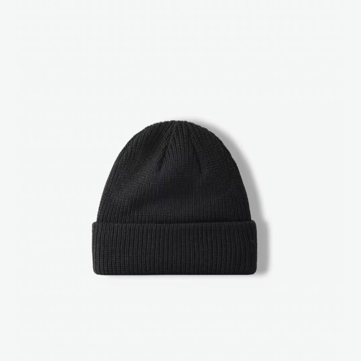 Front view of a timeless black rib-knit acrylic beanie skullcap.