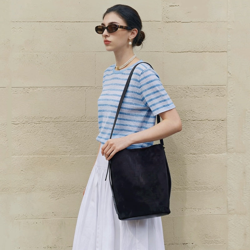Model wearing the black suede bag, showing the long shoulder carry.
