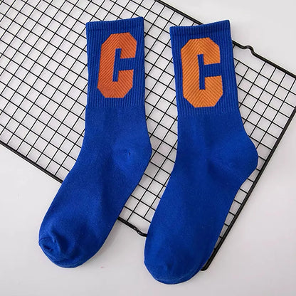 Angled view of  royal blue crew socks with a large orange C letter on each, made from cotton-acrylic blend.