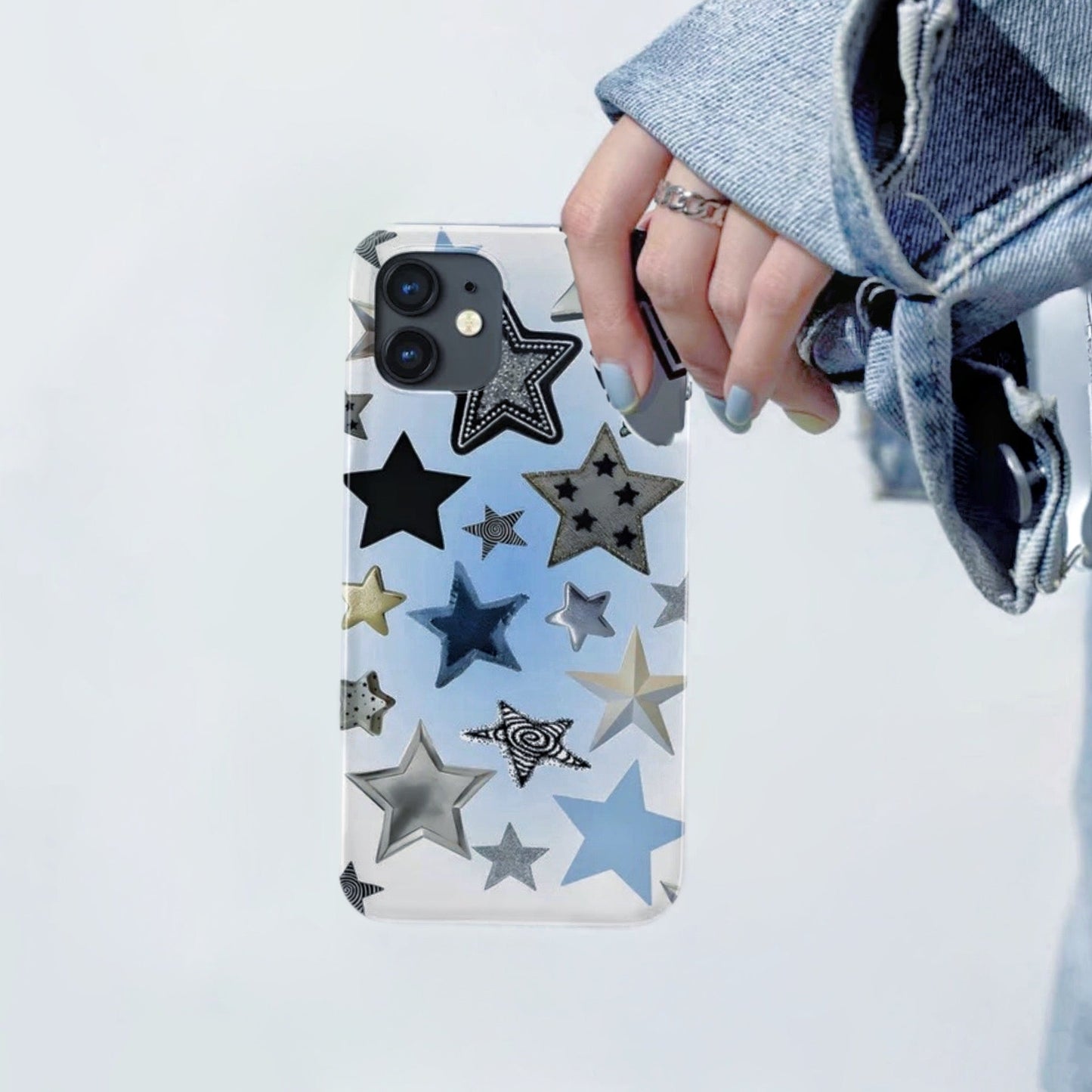 Clear silicone iPhone case with various black, silver, and blue stars. Transparent youthful design accessory.