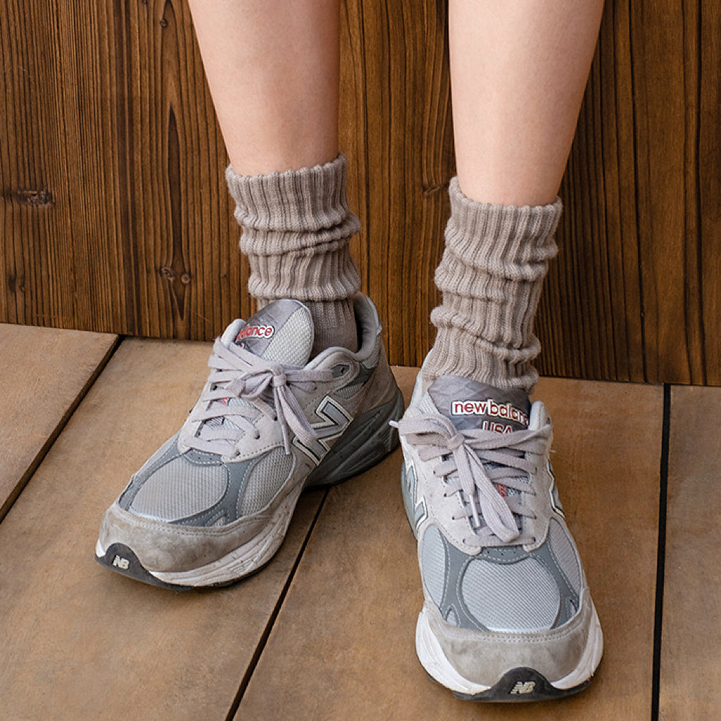 Model wearing a pair of Cotton Slouch Socks in sandy gray, great for daily wear and lounging.