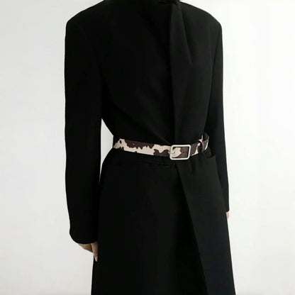 Model wearing a cow print furry belt over a black blazer; chic waist-cinching accessory perfect for office styling.