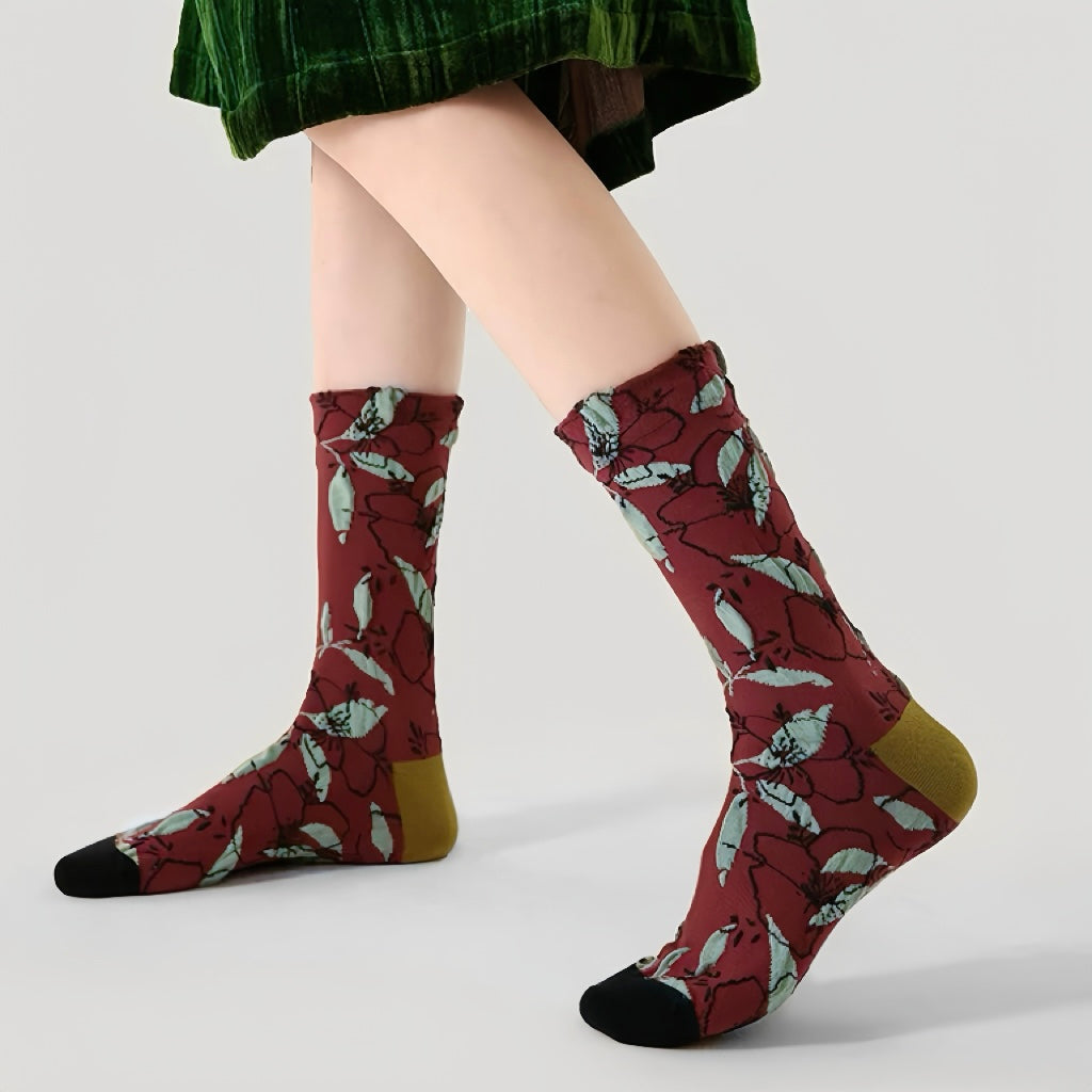 Model wearing a pair of Dancing Flower Socks: Burgundy cotton-polyester crew socks with light green leaf pattern, black toes.