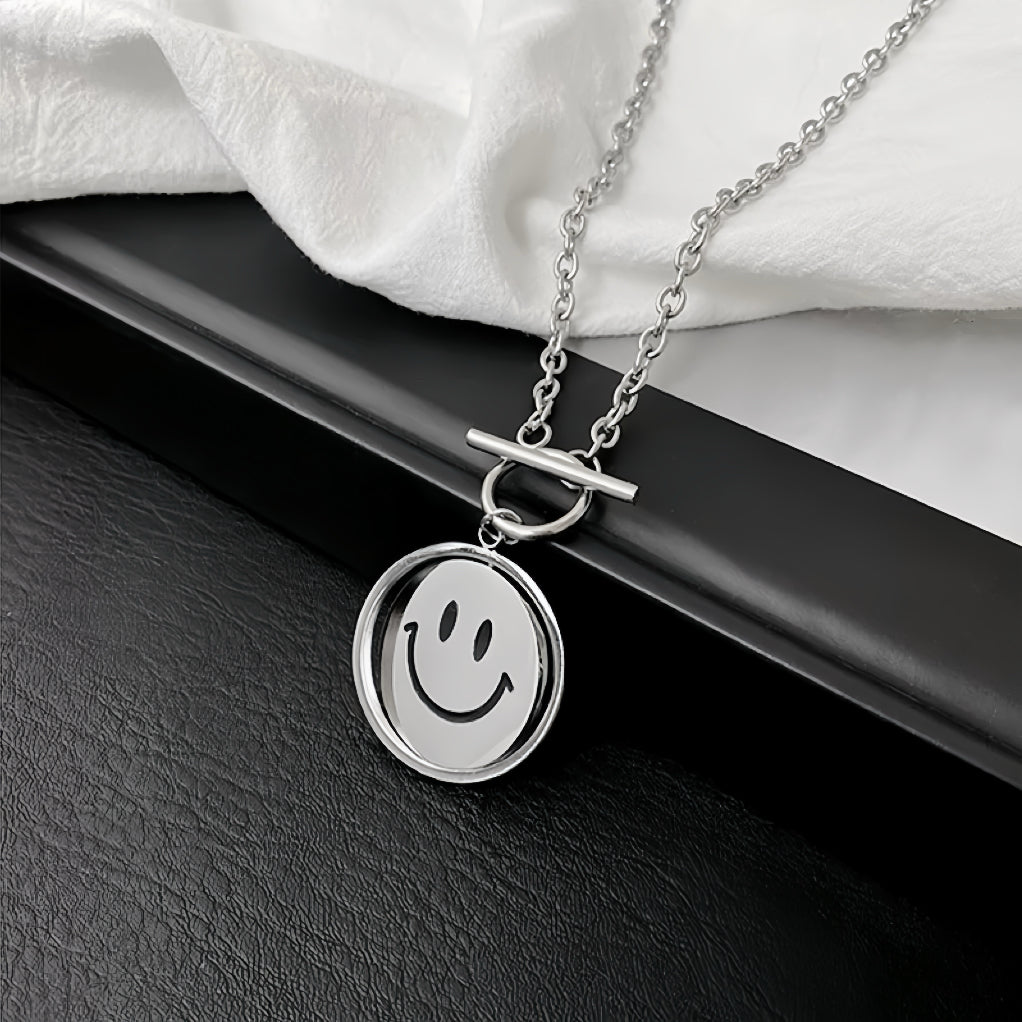 Flat lay of silver titanium steel emoti spin necklace on a dark surface