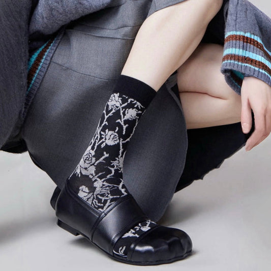 Model wearing a pair of black floral cotton socks, ideal for everyday outfits and sneakers.