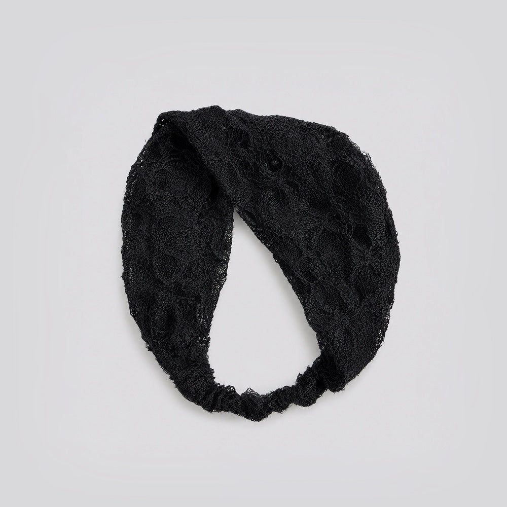 Studio view of the black floral lace headband looped to show its flexible stretch construction and floral pattern.