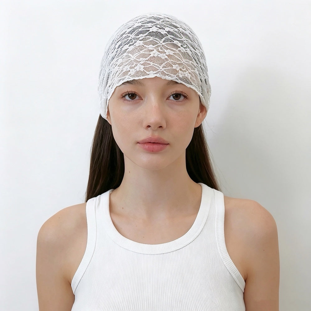 Front view of a model with long straight brown hair wearing the white floral lace headband spread wide across the crown.