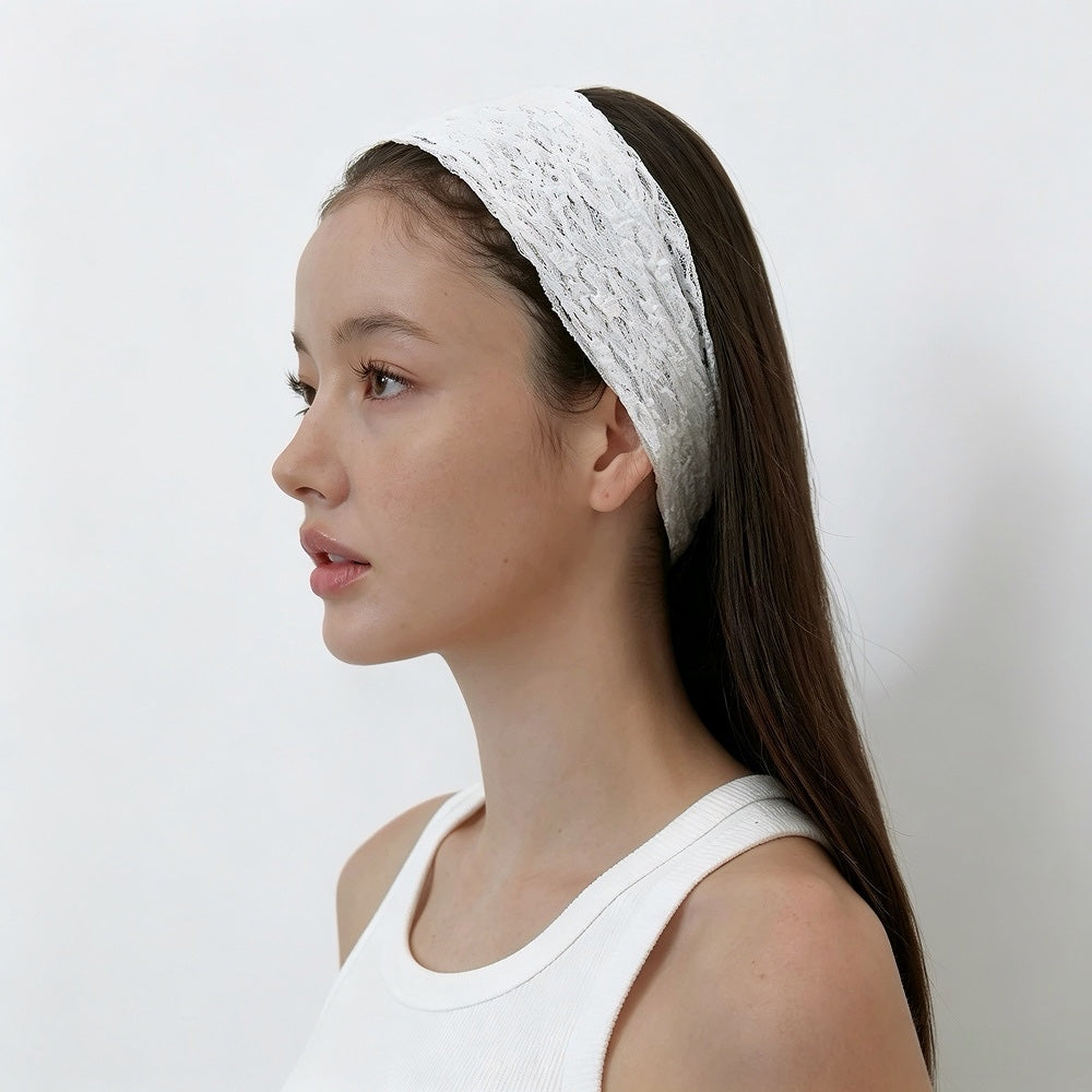 Side profile of a model showing the comfortable fit of the white lace hairband tucked behind the ear.