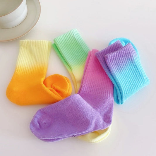 Front view of Four pairs of  gradient rainbow socks in yellow-orange, green-yellow, pink-purple.