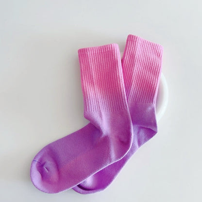 Angled view of  crew-length socks with vibrant pink-to-purple gradient design.