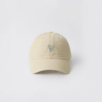 Front view of a beige cotton baseball cap with a subtle embroidered heart.