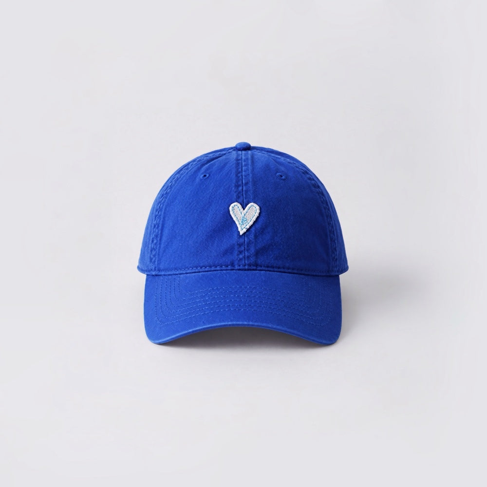 Front angle of a vibrant klein blue cotton cap with white heart embroidery.