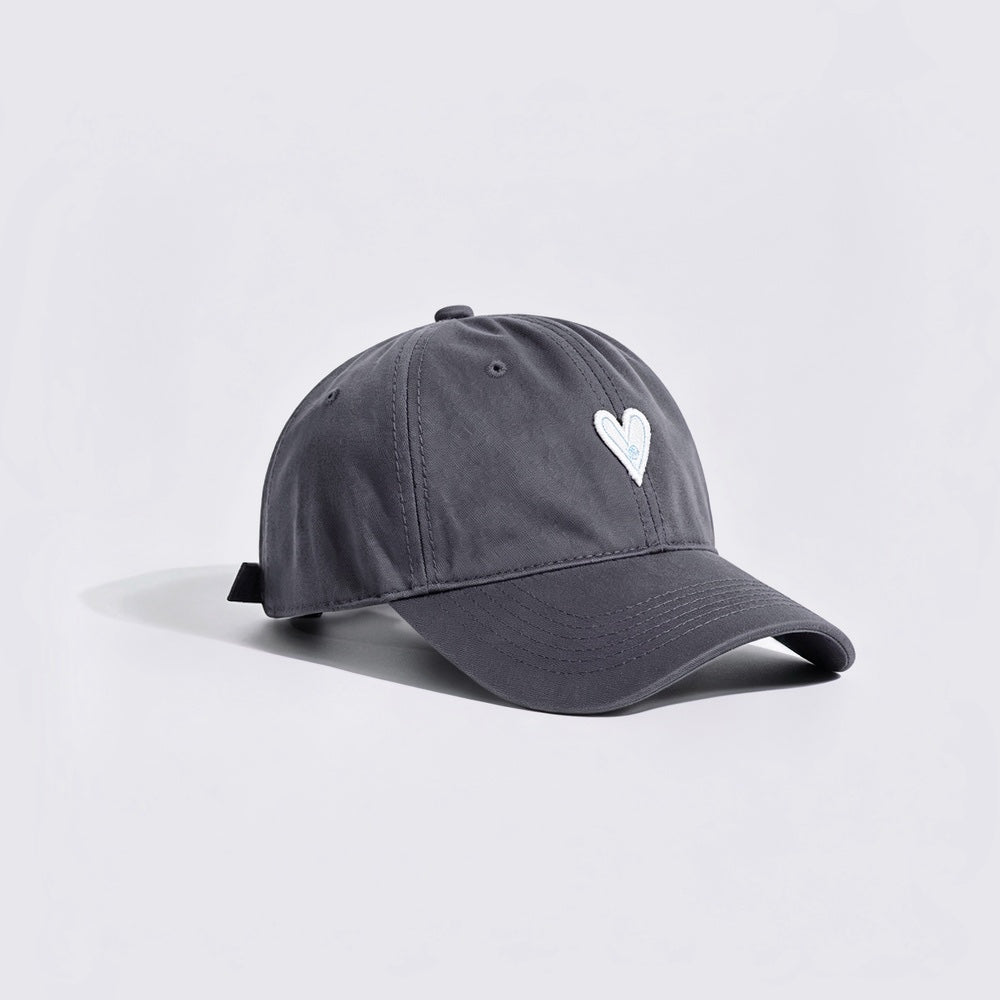 Side view of a charcoal grey baseball hat featuring white heart embroidery.