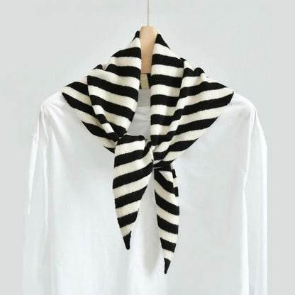 Angled view of the black and white wool striped triangle scarf on a hanger, easy for travel packing and gifting.